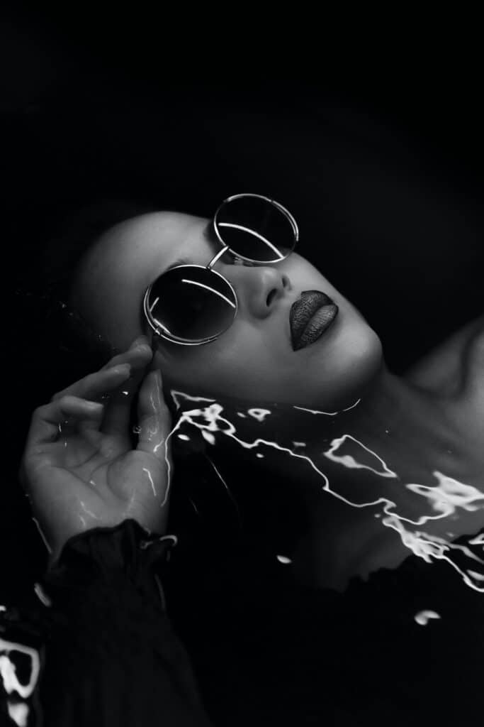 photo en noir et blanc d'un mannequin portant des lunettes de soleil, allongé dans l'eau