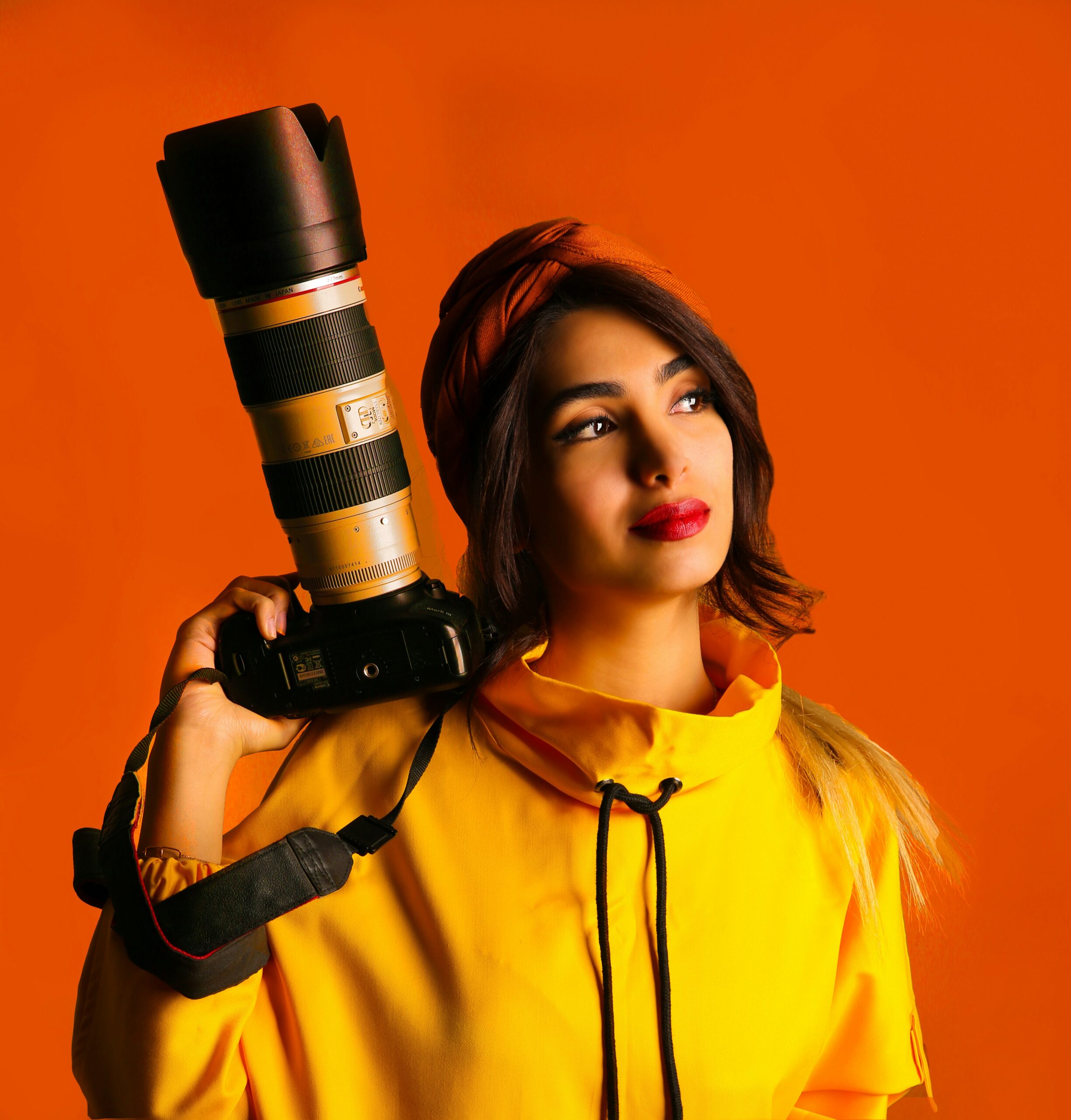 femme photographe vêtue de jaune et tenant un appareil photo échelle 1