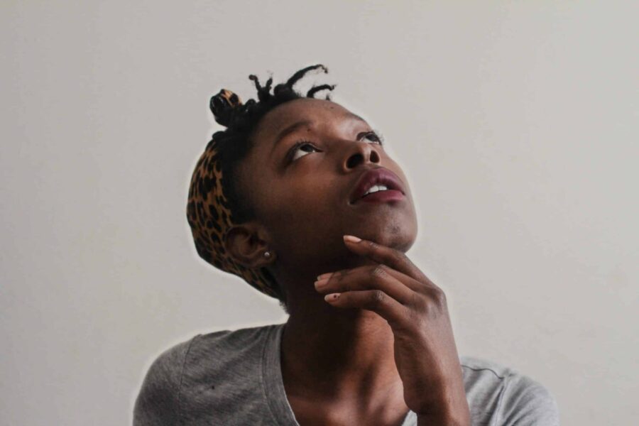 head and shoulders of a black female looking upward her hand gently resting on her chin scaled e1700506546156