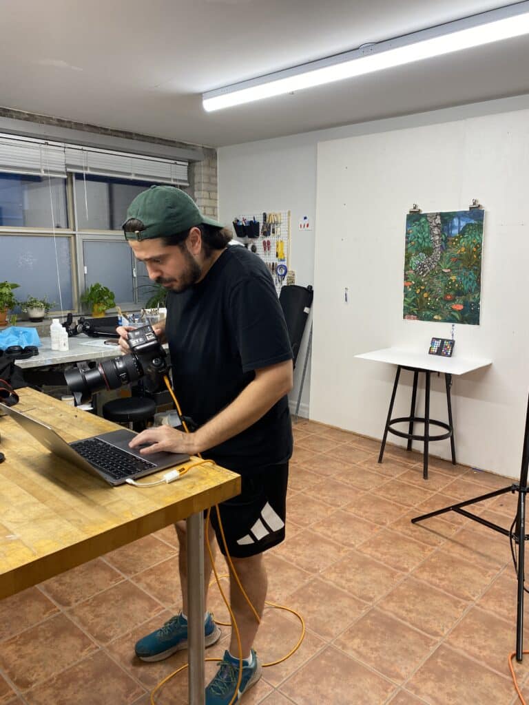 Ibrahim Abusitta revisando imágenes en un portátil atado mientras documenta obras de arte de Stanzie Tooth