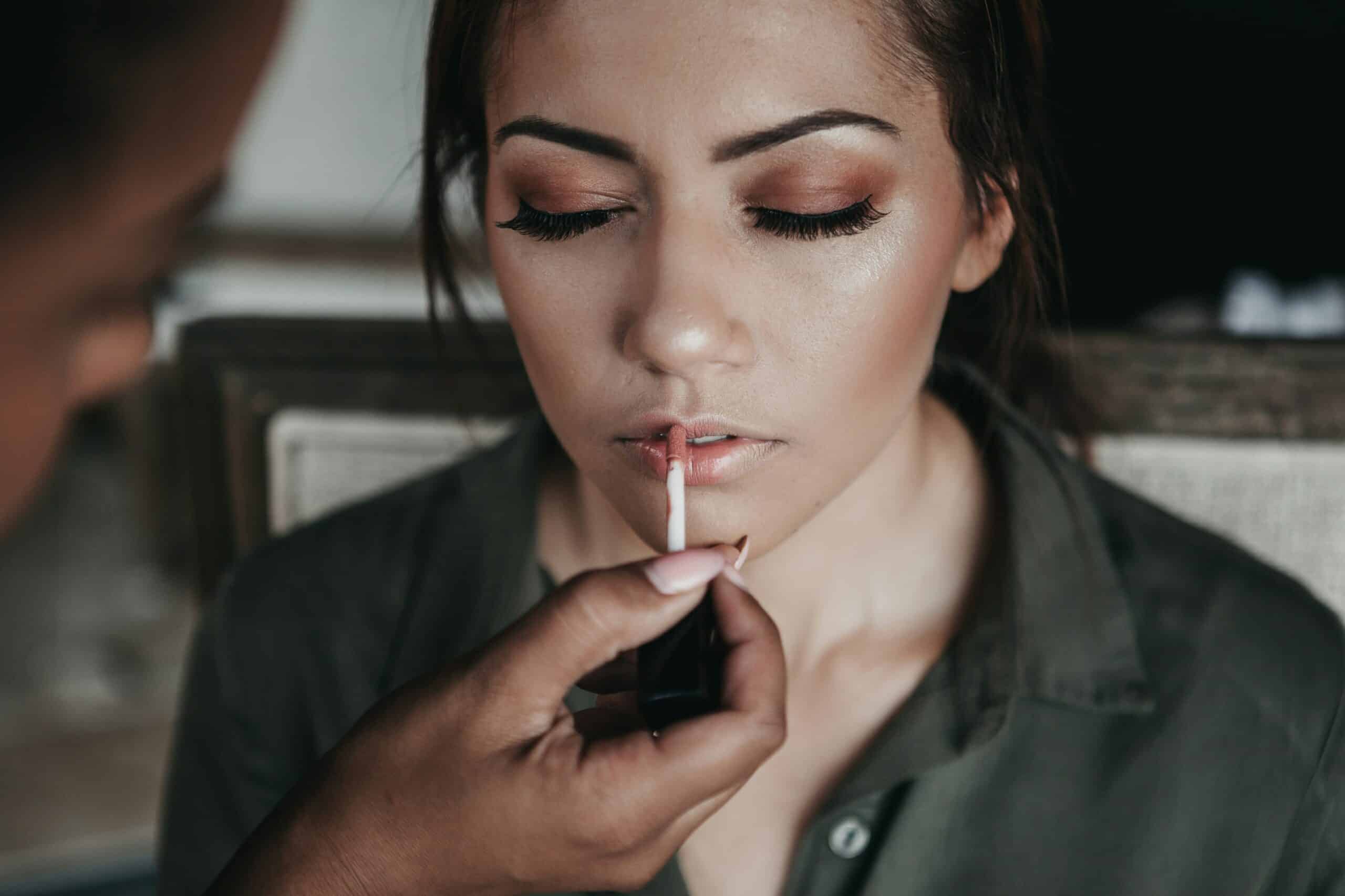 Makeup artist applying lip gloss to a woman scaled 1