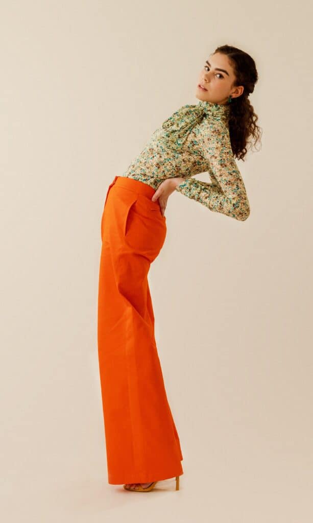 modelo posando con un atrevido pantalón naranja y blusa de flores