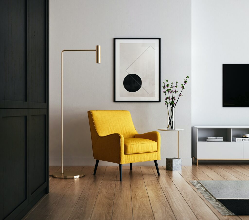 salon moderne minimaliste avec chaise jaune, armoires noires, tableau encadré noir et blanc sur murs blancs et lampadaire en laiton