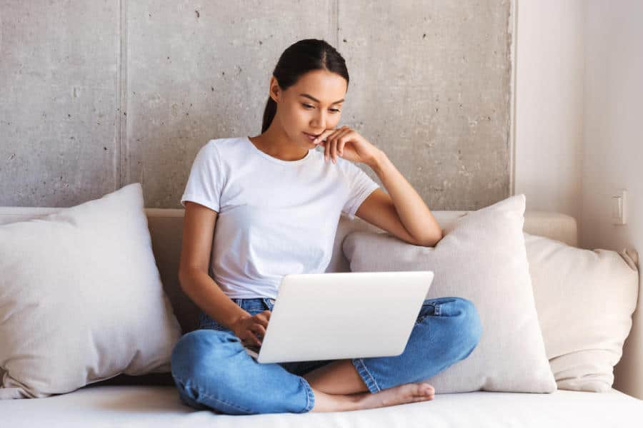 pensive young asian woman using laptop computer YTDQWHK 1