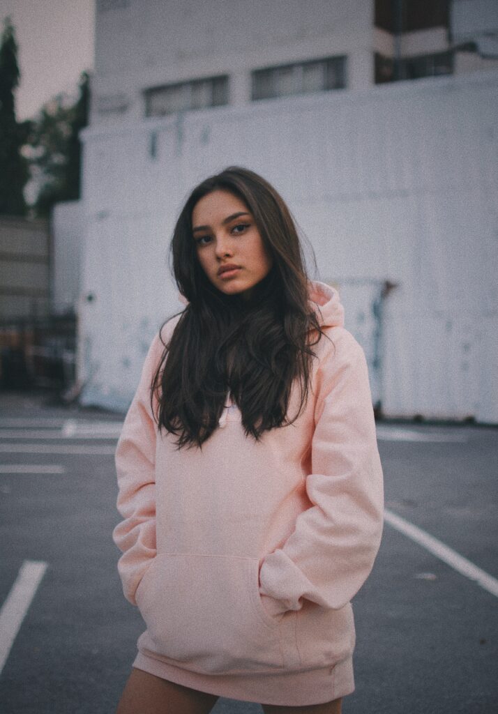 woman with head tilted wearing oversize pink hoodie