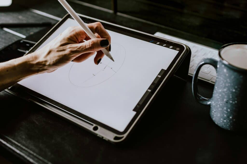 Manos de mujer dibujando en un iPad junto a una taza de café con textura