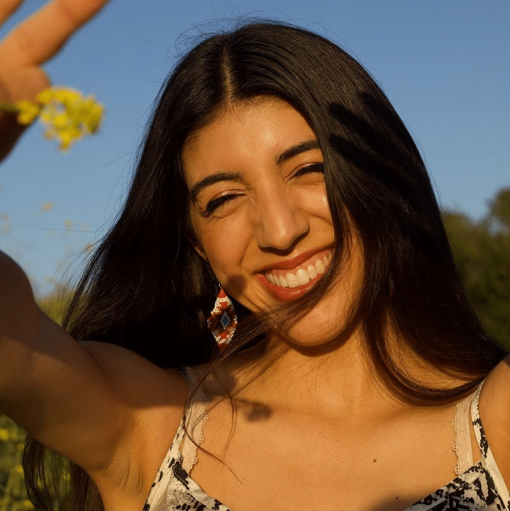 Headshot of Brittany Bravo holding a wildflower in the sunshine.